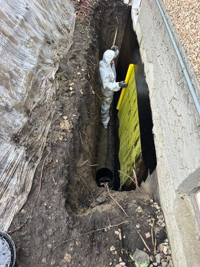 Excavating and sealing a foundation wall in Edmonton, protection board going on over the waterproofing coat