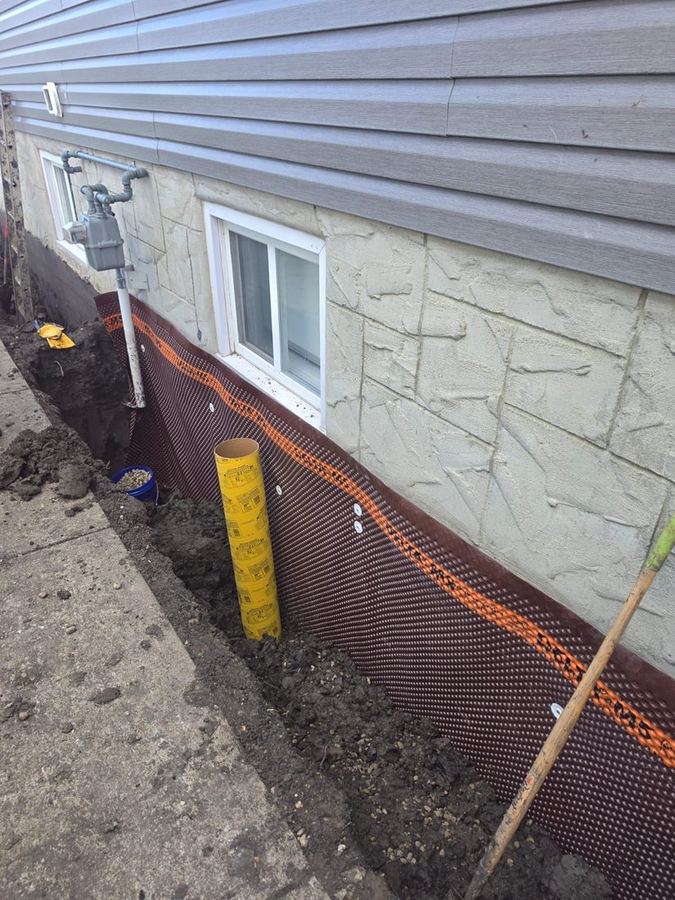 Dimpled drainage membrane fastened to a foundation wall along an open trench
