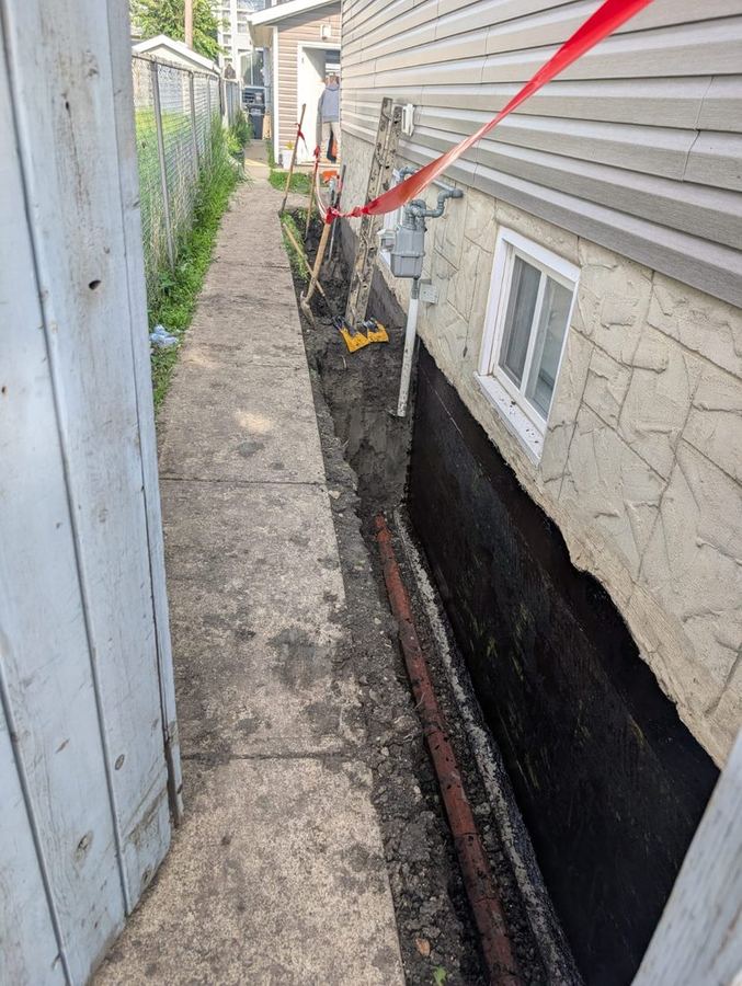 Narrow side yard excavation between a house and a fence with the foundation wall sealed